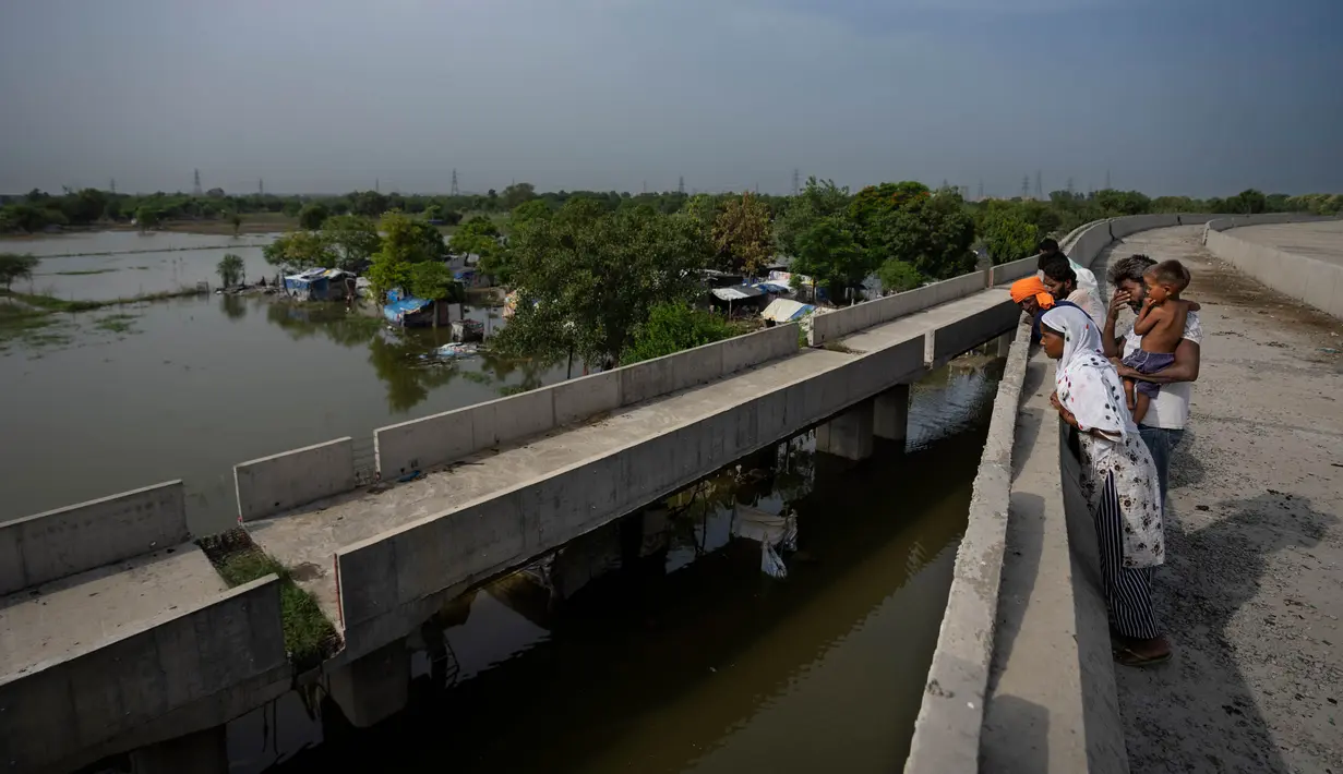 Rekha Devi (kanan) berdiri di samping suaminya ketika memeriksa gubuk mereka yang terendam banjir di tepi Sungai Yamuna yang banjir, di New Delhi, India, Senin (4/9/2023). (AP Photo/Altaf Qadri)