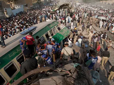 Petugas dibantu warga mengevakuasi korban kecelakaan kereta di Karachi, Pakistan, Kamis (3/11). Kecelakaan itu terjadi akibat kereta penumpang Farid Express bertabrakan dengan kereta penumpang Zakria Express. (AP Photo/Shakil Adil)