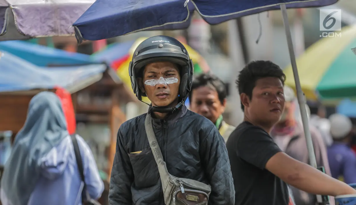 Warga menggunakan odol diwajah untuk menghindari sisa gas air mata pasca bentrok massa dengan aparat di Palmerah, Jakarta, Kamis (26/9/2019). Banyak masyarakat yang melintas dan warga sekitar perih pada mata hingga bersin akibat sisa gas air mata pasca bentrokan kemarin. (Liputan6.com/Faizal Fanani)