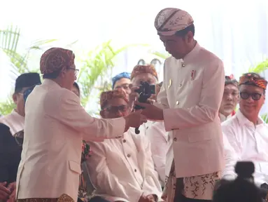 Presiden Joko Widodo (Jokowi) menerima kujang, senjata khas Sunda dalam prosesi penganugerahan gelar Pinisepuh dari Paguyuban Pasundan di Bandung, Minggu (11/11). Paguyuban Pasundan adalah ormas Sunda yang berdiri sejak 1913. (Liputan6.com/Angga Yuniar)