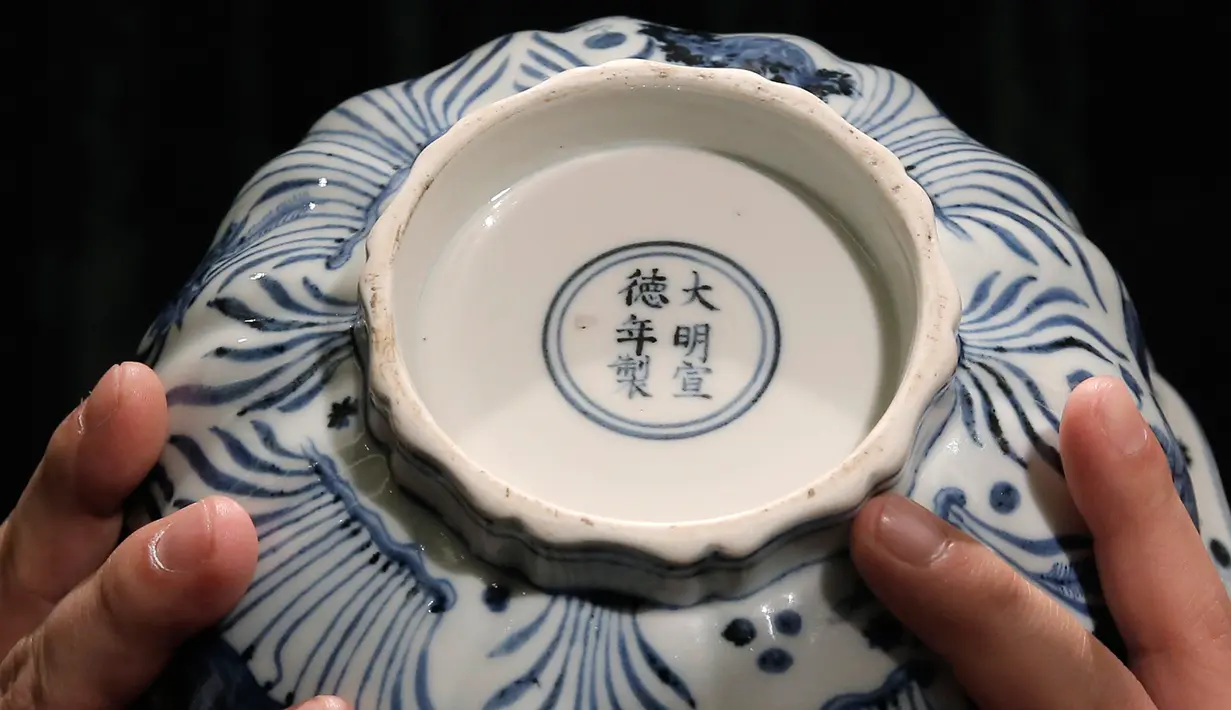 Pekerja memperlihatkan bagian bawah mangkuk Xuande Lobel "Fish Pond" saat ditampilkan di pelelangan Sotheby di Hong Kong (8/3). Mangkuk Xuande Lobel "Fish Pond" ini akan dilelang pada tanggal 5 April. (AP Photo / Kin Cheung)