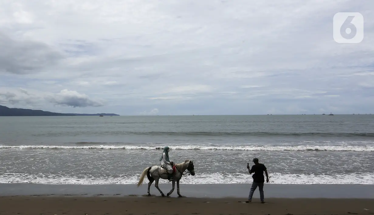 Warga naik kuda di Pantai Pelabuhan Ratu, Kabupaten Sukabumi, Jawa Barat, Jumat (12/11/2021). Pantai Pelabuhan Ratu menjadi tempat wisata favorit warga Jawa Barat serta Jakarta dan sekitarnya. (Liputan6.com/Johan Tallo)