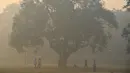 Warga bermain kriket di bawah pohon saat asap tebal menyelimuti New Delhi, India (20/10). New Delhi diselimuti asap tebal sehari setelah jutaan orang menyalakan petasan merayakan Diwali Festival. (AFP Photo/Dominique Faget)