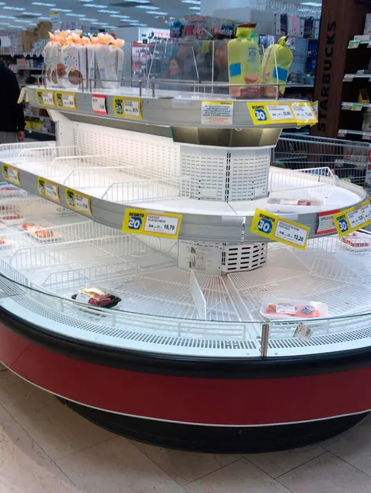 Rak-rak kosong terlihat di sebuah supermarket di Rozzano, dekat Milan, Minggu (23/2/2020). Orang-orang memborong perlengkapan dan bahan-bahan kebutuhan pokok karena tak mau keluar rumah menyusul dua warga Italia yang dipastikan meninggal karena Virus Corona COVID-19 . (AP/Antonio Calanni)