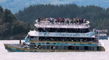 Penumpang terlihat berada di atas kapal wisata Almirante sesaat sebelum tenggelam di sebuah waduk di Kolombia barat daya, Minggu (25/6). Sedikitnya sembilan orang meninggal dunia dan 28 lainnya hilang dalam peristiwa itu. (Juan QUIROZ/AFPP)