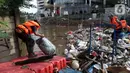 Petugas UPK Badan Air DLH Provinsi DKI Jakarta berjibaku membersihkan tumpukan sampah yang menghalangi aliran air Kali Mampang di Jalan Pejaten Raya, Jakarta, Sabtu (20/2/2021). Aliran air Kali Mapang di Jalan Pejaten Raya meluap akibat sumbatan tumpukan sampah. (Liputan6.com/Helmi Fithriansyah)