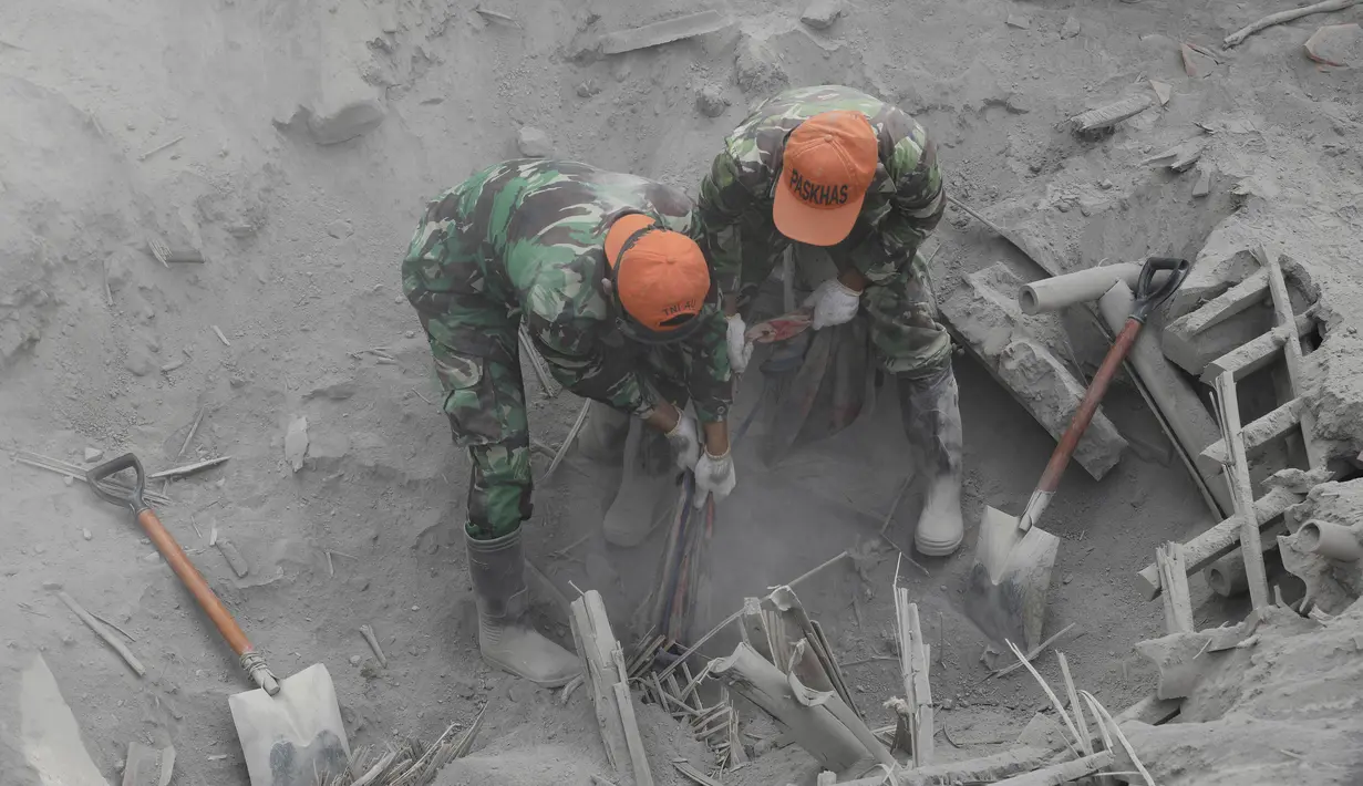 Prajurit TNI mencari korban di lokasi tertimbunnya rumah di bawah abu vulkanik letusan Gunung Semeru di Desa Candi Murni, Lumajang, Jawa Timur, Selasa (7/12/2021). Tim Search and Rescue (SAR) Gabungan terus melakukan pencarian korban erupsi Gunung Semeru. (AP Photo/Trisnadi)