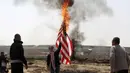 Pemuda Palestina membakar bendera Amerika Serika saat melakukan aksi protes di perbatasan Gaza dengan Israel (6/4). Ketegangan terus memanas, seiring seruan Friday of Fire atau Pertempuran Jumat yang digaungkan warga Palestina. (AFP Photo/Menahem Kahana)