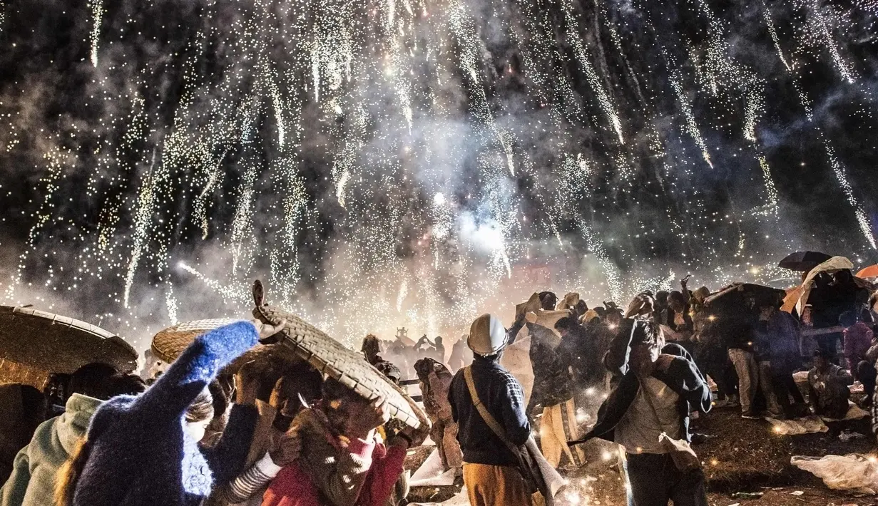 Pengunjung melindungi diri dari percikan kembang api balon udara panas dalam Festival Tazaungdaing di Taunggyi, Myanmar (12/11). Festival ini merupakan salah satu perayaan paling indah dan berbahaya di Asia.(AFP/Ye Aung Kamis)