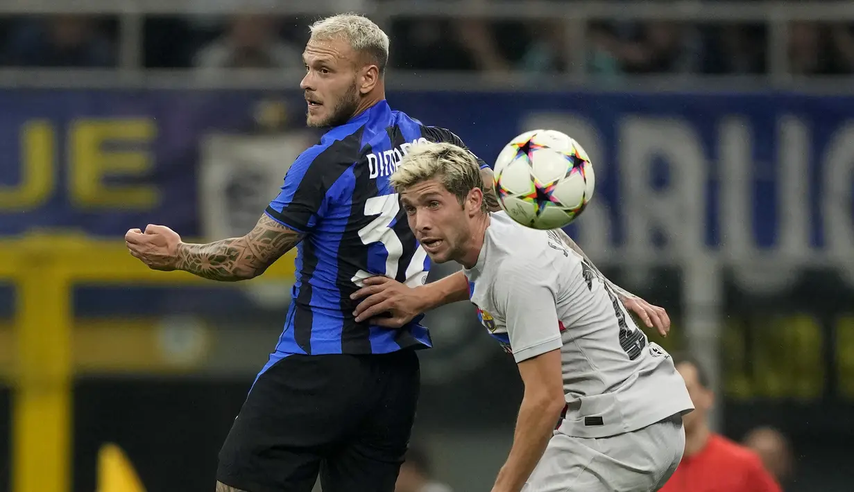 Bek Inter Milan Federico Dimarco melompat untuk merebut bola dari penyerang Barcelona Raphinha pada matchday ketiga Grup C Liga Champions 2022/2023 di Giuseppe Meazaa, Rabu dini hari WIB (5/10/2022). Gol kemenangan tim wakil Italia dilesakkan Hakan Calhanoglu. (AP Photo/Antonio Calanni)
