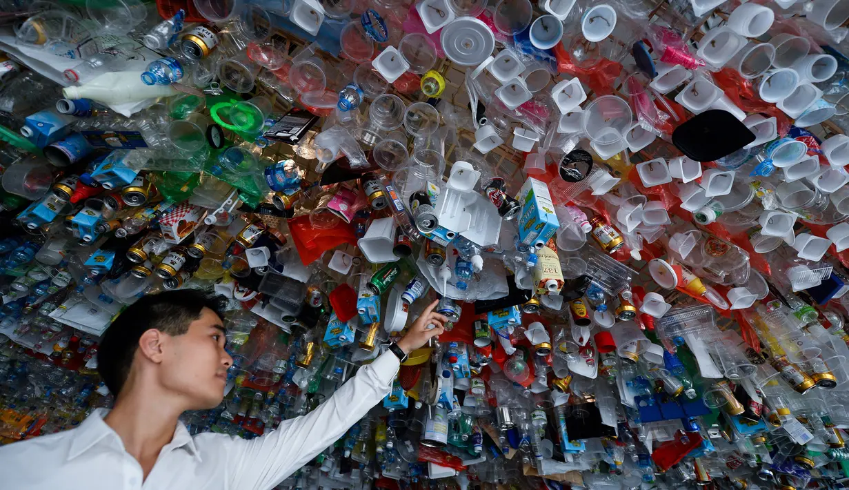 Seorang pria melihat instalasi seni gantung sekelompok seniman yang terbuat dari sisa-sisa plastik, kaleng dan wadah di sebuah pameran "Reduce the Litter" di Pusat Kebudayaan Prancis di Hanoi (15/7/2019). Pameran ini mengambil perspektif tentang produksi dan konsumsi. (AFP Photo/Nhac Nguyen)