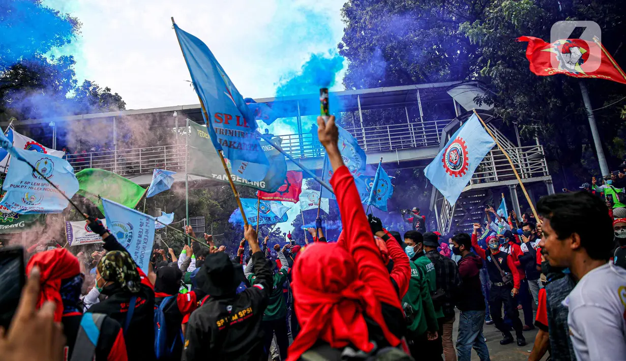 Massa buruh menyalakan asap suar saat unjuk rasa di Patung Kuda, Jakarta, Kamis (22/10/2020). Aksi gabungan buruh, petani, mahasiswa, dan pelajar dilakukan untuk menyuarakan penolakan pengesahan UU Cipta Kerja dan meminta Presiden mengeluarkan Perppu. (Liputan6.com/Faizal Fanani)