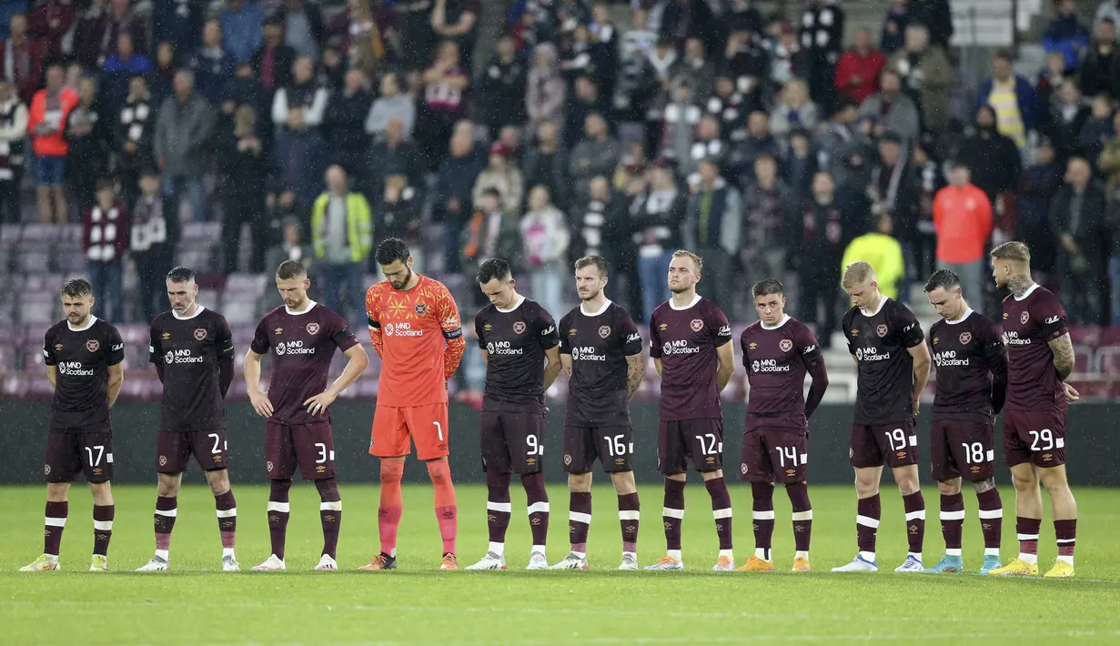 Pemain Hearts berdiri mengenakan ban lengan hitam sebelum babak kedua setelah pengumuman meninggalnya Ratu Elizabeth II, selama pertandingan sepak bola Grup A Liga Konferensi Eropa antara Heart of Midlothian dan Istanbul Basaksehir di Tynecastle Park, Edinburgh, Kamis, 8 September 2022. (Robert Perry/PA via AP)