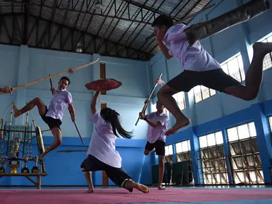 Seorang gadis menangkis serangan empat anak laki-laki yang menggunakan pedang selama berlatih Krabi Krabong di sekolah Thonburee Woratapeepalarak, Thonburi, Bangkok (8/7/2019). Krabi Krabong merupakan seni bela diri Thailand yang dipersenjatai pisau dan perisai kayu. (AFP Photo/Lillian Suwanrumpha)