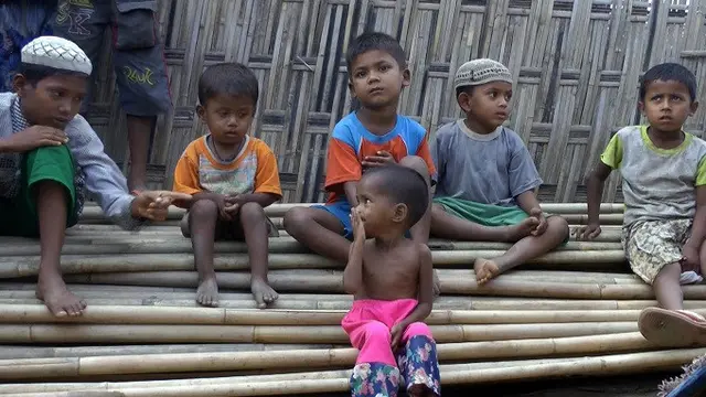 Anak-anak Rohingya tengah duduk di atas tumpukan pohon bambu di kamp pengungsi Dar Paing, di utara Sittwe, Rakhine