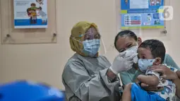 Dokter memeriksa suhu tubu balita sebelum mengikuti imunisasi di Puskesmas Kecamatan Jatinegara, Jakarta, Kamis (26/11/2020). Kegiatan imunisasi menerapkan protokol 3M, baik bagi dokter, sang ibu, maupun balita agar program Menuju Indonesia Sehat dapat tercapai. (merdeka.com/Iqbal S. Nugroho)