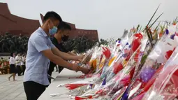 Sejumlah warga menaruh bunga saat mengunjungi Mansu Hill untuk memberi penghormatan terhadap patung-patung perunggu dari Kim Il-sung dan Kim Jong-il pada peringatan 26 tahun kematian Kim Il-sung di Pyongyang, Korea Utara, Rabu (8/7/2020). (AP Photo/Jon Chol Jin)