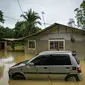 Sebuah mobil terendam banjir di Sementeh, dekat Lanchang di negara bagian Pahang Malaysia (6/1/2021). Hujan deras terus melanda sebagian wilayah Malaysia, menyebabkan ribuan orang dievakuasi di negara bagian selatan Johor dan beberapa bagian jalan raya Pantai Timur di Pahang. (AFP/Mohd Rasfan)