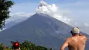Wisatawan mengamati Gunung Agung yang kembali meletus terlihat dari Karangasem, Bali, Selasa (3/7). Kolom abu teramati berwarna putih hingga kelabu dengan intensitas tebal condong ke arah barat. (AP Photo/Firdia Lisnawati)