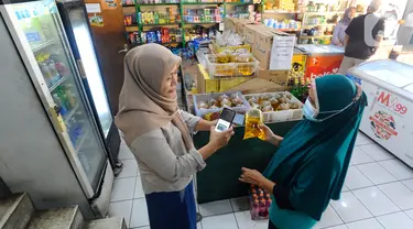 Pedagang melakukan scan KTP pembeli minyak goreng curah di Toko Tjandra, Cinere, depok, Jumat (03/06/2022). Paska dicabutnya kebijakan subsidi minyak goreng curah, pembeli minyak goreng curah di pasaran diwajibkan menyertakan kartu tanda penduduk (KTP) dengan maksimal 1 ktp untuk 2 liter minyak goreng curah seharga Rp 14.000/liter. (merdeka.com/Arie Basuki)