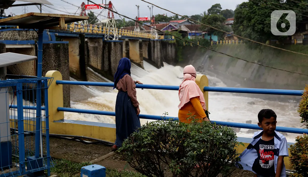 Warga melihat debit air di Bendung Katulampa, Bogor, Jawa Barat, Jumat (19/2/2021). Meski sempat mengalami kenaikan debit air pada Jumat (19/2) pagi, namum sekitar pukul 15.00 WIB, debit air di Bendung Katulampa berada di zona hijau dengan ketinggian sekitar 50 cm. (Liputan6.com/Helmi Fithriansyah)