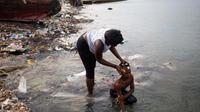 Seorang perempuan memandikan putrinya di pantai era mereka bersiap-siap buat pergi ke gereja, di Warf of Port Cite Soleil di Port-au-Prince, Haiti (17/3). Cité Soleil merupakan lingkungan yang sangat bapet dengan padat penduduk. (AP Photo/Dieu Nalio Chery)