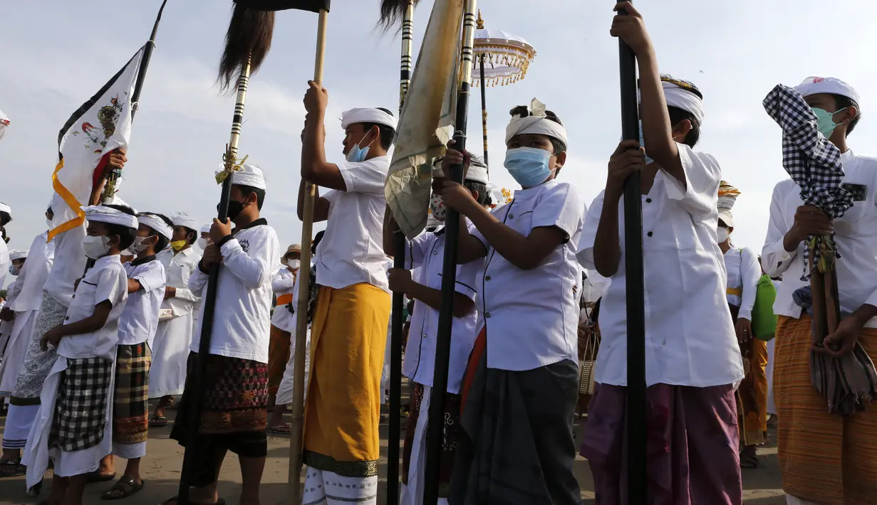 Anak-anak mencelupkan kaki ke laut saat mengikuti ritual Melasti di Bali, Senin (28/2/2022). Ritual yang dilakukan menjelang Hari Raya Nyepi umat Hindu ini diadakan untuk menyucikan alam semesta dari pengaruh buruk, perbuatan dan pikiran buruk. (AP Photo/Firdia Lisnawati)