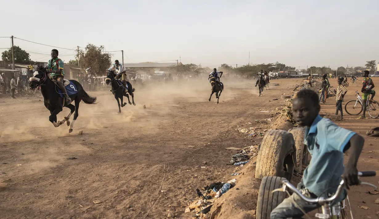 Seorang anak menonton pacuan kuda di Ouagadougou (30/1/2022). Koboi terkenal memenangkan jutaan Franc Afrika Barat dari balapan dan diam-diam melatih kuda di malam hari untuk melakukan dressage, beberapa bahkan menyebut diri mereka koboi dan berpakaian sesuai. (AFP/John Wessels)