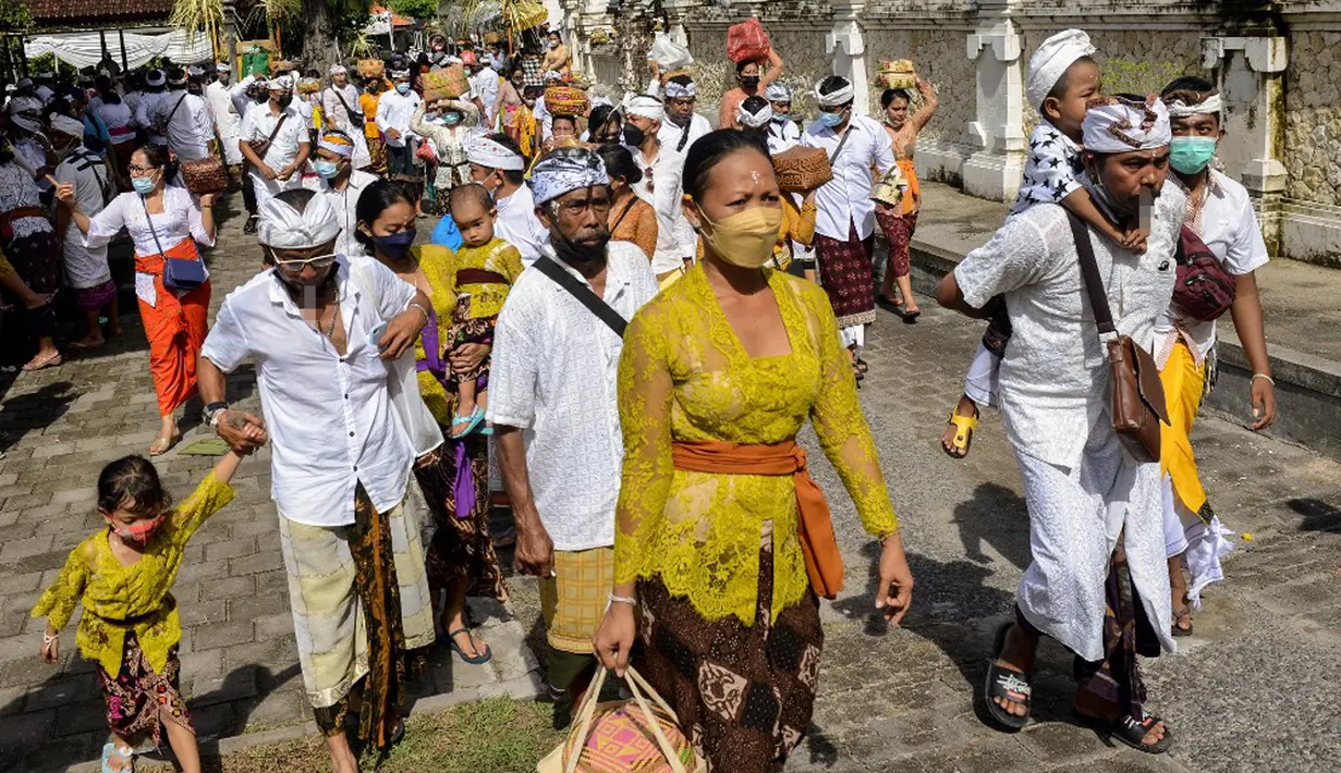Umat Hindu membawa sesaji saat akan berdoa pada perayaan Hari Raya Kuningan di Pura Sakenan, Pulau Serangan, Denpasar, Bali, Sabtu (20/11/2021). Kuningan merupakan hari terakhir perayaan Galungan yang diyakini sebagai hari naiknya roh suci leluhur kembali ke surga. (Sonny TUMBELAKA/AFP)