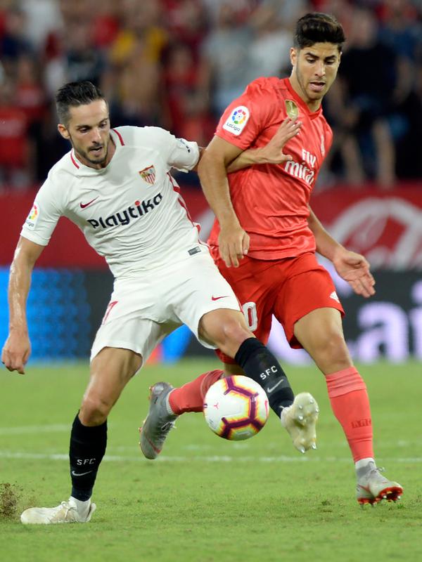 Gelandang Real Madrid, Marco Asensio berebut bola dengan gelandang Sevilla Pablo Sarabia saat bertanding pada lanjutan La Liga Spanyol di stadion Sanchez Pizjuan (26/9).  Sevilla menang telak 3-0 atas Madrid. (AFP Photo/Cristina Quicler)