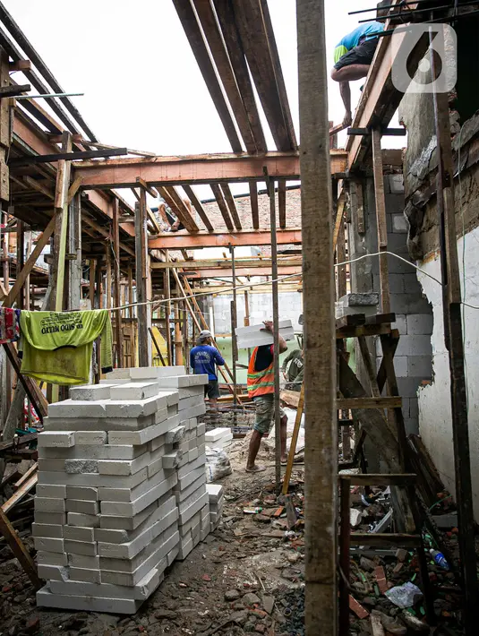 Para pekerja menyelesaikan pembangunan rumah panggung di dekat bantaran Kali Ciliwung, Kampung Melayu, Jakarta, Rabu (7/4/2021). Pemerintah Provinsi DKI Jakarta melakukan renovasi terhadap 40 hunian warga Kampung Melayu menjadi rumah panggung. (Liputan6.com/Faizal Fanani)