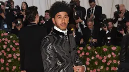 Pembalap Mercedes, Lewis Hamilton berpose saat tiba menghadiri Met Gala 2019 di Metropolitan Museum of Art di New York, AS (6/5/2019). Lewis Hamilton menjadi pusat perhatian dengan setelan jas hitam berdesain zig-zag metalik dan ikat kepala bertatahkan permata.  (AP Photo/Evan Agostini)