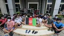 Pengungsi Afghanistan mengibarkan bendera negaranya untuk menunjukkan identitasnya di sebuah kamp pengungsi di Bekasi, Jawa Barat (20/8/2021). Mereka tidak bersedia kembali ke negaranya, terutama setelah Taliban mengambil alih kekuasaan dari pemerintahan Presiden Ashraf Ghani. (AFP/Bay Ismoyo)