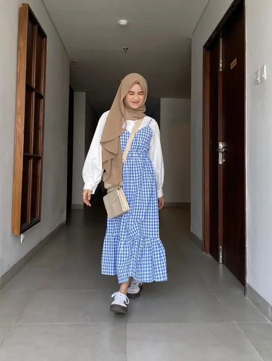 Tampil feminin, padukan slip dress motif plaid warna biru dengan kemeja warna putih. (Instagram/aishaibrahimmm).