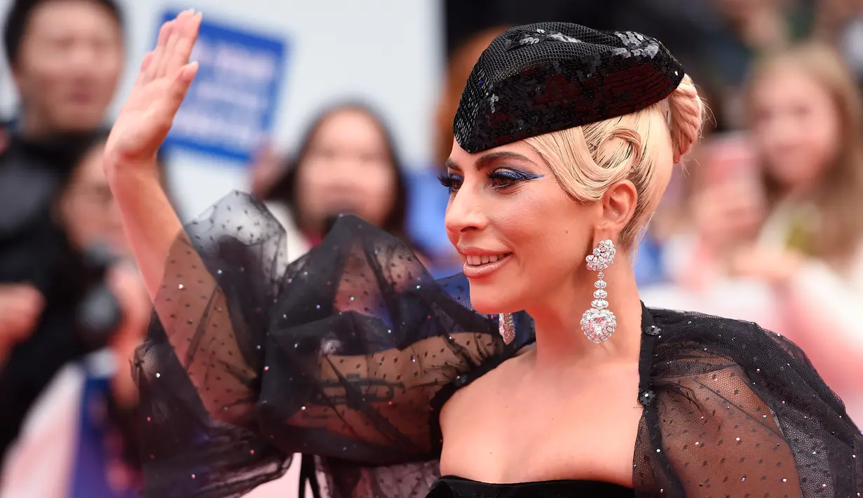 Lady Gaga menyapa penggemar saat tiba menghadiri pemutaran film "A Star is Born" selama Toronto International Film Festival 2018 di Toronto (9/9). Lady gaga tampil menggenakan gaun berwarna hitam. (AP Photo/Nathan Denette)