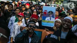 Massa Gentari (Genarasi Cinta Negeri) membawa poster dalam aksi dukungan kepada Gubernur DKI, Anies Baswedan di Balai Kota DKI Jakarta, Selasa (14/1/2020). Mereka mengawal Anies Baswedan agar menyelesaikan program kerja sebagai Gubernur DKI terkait penanganan banjir. (Liputan6.com/Faizal Fanani)