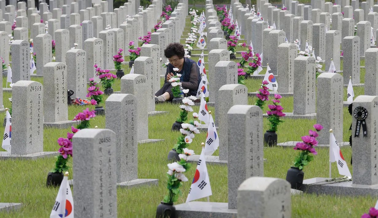 Warga Korsel, Lee Jin-yeo berdoa di depan nisan sepupu lelaki ayahnya yang gugur untuk negara pada Memorial Day di Pemakaman Nasional Seoul, Kamis (6/6/2019). Memorial Day didedikasikan untuk mengingat prajurit dan warga sipil yang gugur selama perang Korea antara 1950-1953. (AP/Ahn Young-joon)