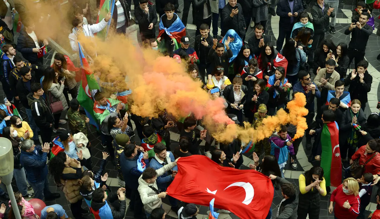 Rakyat Azerbaijan mengibarkan bendera nasional dan Turki di Baku, Azerbaijan, Selasa (10/11/2020). Armenia dan Azerbaijan mengumumkan perjanjian damai untuk menghentikan pertempuran atas wilayah Nagorno-Karabakh di Azerbaijan berdasarkan pakta yang ditandatangani dengan Rusia. (AP Photo)