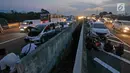 Pemudik beristirahat sembari menyantap makanan untuk berbuka puasa di pinggir ruas jalan tol Cipali KM 187, Kabupaten Cirebon, Jawa Barat, Kamis (30/5/2019). Sejumlah pemudik memilih menggunakan bahu jalan ruas tol untuk berbuka puasa karena penuhnya rest area. (Liputan6.com/Herman Zakharia)