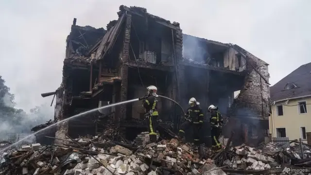 Petugas penyelamat memadamkan api di sebuah rumah yang hancur akibat serangan Rusia di desa Markhalivka, wilayah Kyiv, Ukraina, Minggu, 25 Mei 2025. (AP/Evgeniy Maloletka)