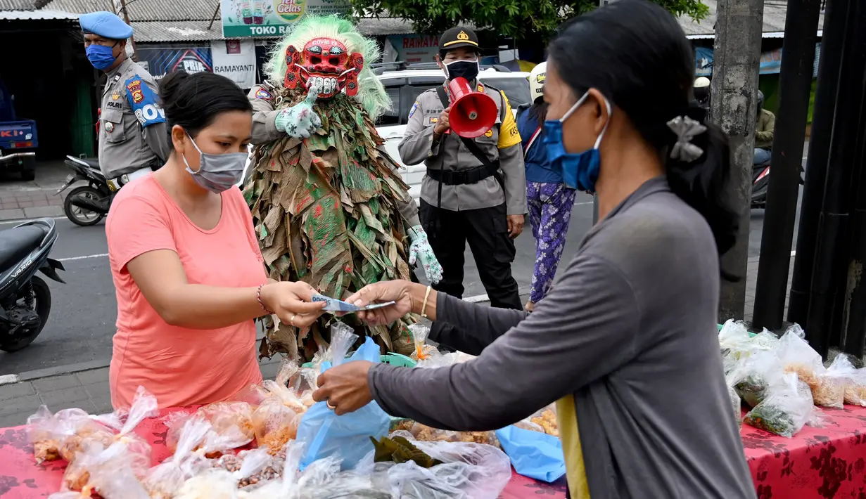Polisi mengenakan topeng menyeramkan yang disebut "Leak" saat sosialisasi langkah-langkah pencegahan COVID-19 di pasar tradisional di Kerobokan, Denpasar, Kamis (14/5/2020). Kegiatan itu untuk mengimbau masyarakat terus melakukan berbagai upaya pencegahan penyebaran COVID-19. (SONNY TUMBELAKA/AFP)