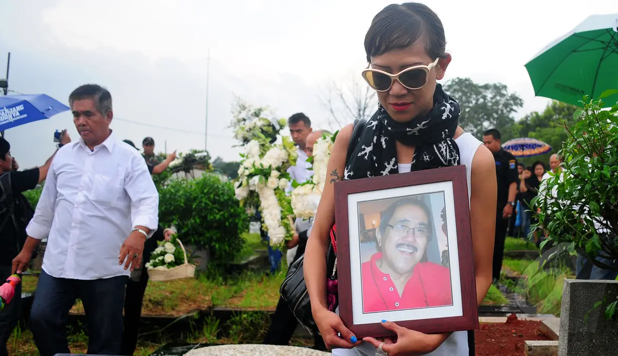 Salah satu kerabat membawa foto Frans Tumbuan yang dimakamkan di TPU Tanah Kusir, Kebayoran Lama, Jakarta, Rabu (25/3/2015). (Liputan6.com/Yoppy Renato)