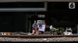 Seorang warga duduk saat kereta melintas di bantaran rel kawasan pemukiman padat Pejompongan di tengah pandemi COVID-19, Jakarta, Kamis (28/1/2020). Dibandingkan dengan hasil sensus sebelumnya, jumlah penduduk DKI Jakarta terus meningkat. (Liputan6.com/Johan Tallo)