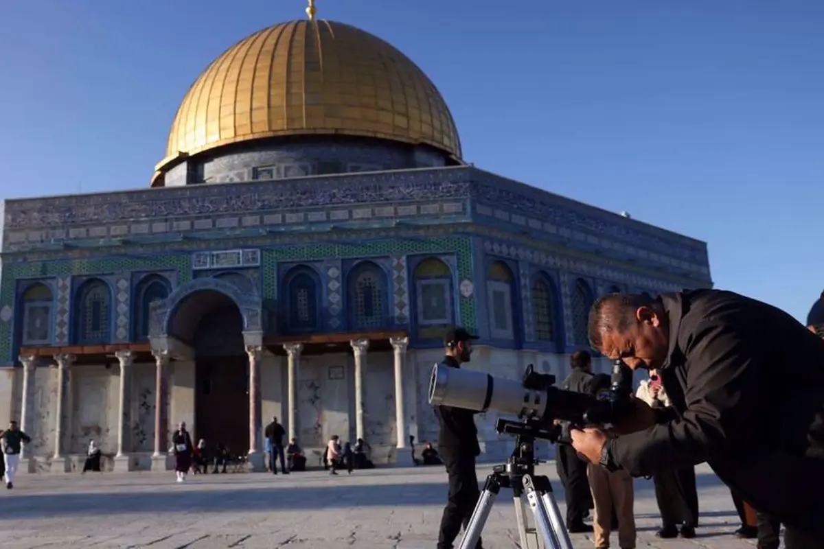 Seorang pria menggunakan teleskop saat mencari bulan sabit untuk menandai dimulainya bulan suci Ramadan di kompleks Masjid Al-Aqsa, Yerusalem, pada 28 Februari 2025.