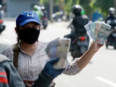 Penjual jasa penukaran uang menawarkan uang baru berbagai pecahan kepada pengguna jalan di kawasan Bintaro Sektor 2, Jakarta Selatan, Selasa (12/05/2020). Menjelang perayaan Lebaran, jasa penukar uang keliling yang berada di pinggir jalan-jalan utama mulai bermunculan. (merdeka.com/Dwi Narwoko)