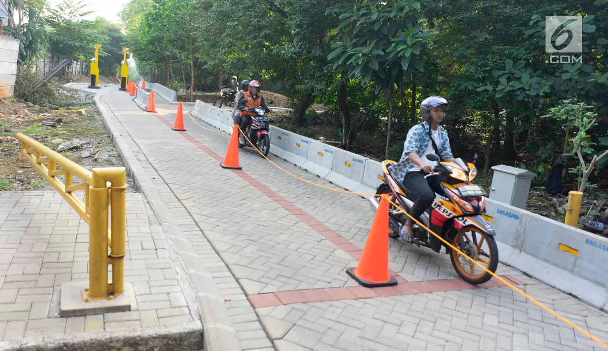 Pengendara motor melintasi akses pintu masuk dan keluar Universitas Indonesia di Depok, Jawa Barat, Selasa (16/7/2019). Penerapan uji coba sistem masuk parkir UI berbayar yang menyebabkan kemacetan panjang membuat gerbang tiket pembayaran kembali dinonaktifkan. (Liputan6.com/Immanuel Antonius)
