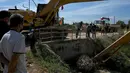 Pekerja kota mencoba memblokir kanal untuk melindungi rumah dari air banjir yang meningkat setelah hujan lebat di pinggiran Phnom Penh, Kamboja (26/10/2021). (AFP/Tang Chhin Sothy)