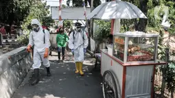 Petugas Palang Merah Indonesia (PMI) Jakarta Timur berpakaian APD menyemprotkan disinfektan di permukiman Kampung Tengah, Kramat Jati, Minggu (23/8/2020). Penyemprotan sebagai langkah sterilisasi permukiman setelah warga di Kampung Tengah dilaporkan terpapar Covid-19. (Liputan6.com/Iqbal Nugroho)