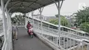 Warga dan pengendara motor melintasi jembatan penyeberangan orang (JPO) Stasiun Pasar Minggu Baru, Jakarta, Selasa (10/3/2020). JPO tersebut kerap disalahgunakan pengendara motor sebagai jalan alternatif untuk mempersingkat jarak tempuh meski rambu larangan sudah dipasang. (merdeka.com/Iqbal Nugroho