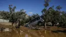 Seorang pria berjalan melewati sebuah mobil yang terbawa air banjir setelah badai di desa Kineta, Athena (25/11/2019). Ratusan rumah terendam banjir setelah badai semalam menerjang daerah barat Athena. (AP Photo/Petros Giannakouris)